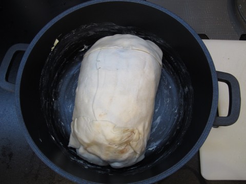 Stendete la pasta sfoglia e adagiate sopra di essa il coniglio ripieno, arrotolatelo e sigillate bene tutti i bordi. Imburrate una casseruola, mettete all'interno il coniglio e coprite con il coperchio.